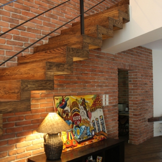 Ceglana ściana z drewnianymi schodami  Elkamino dom
